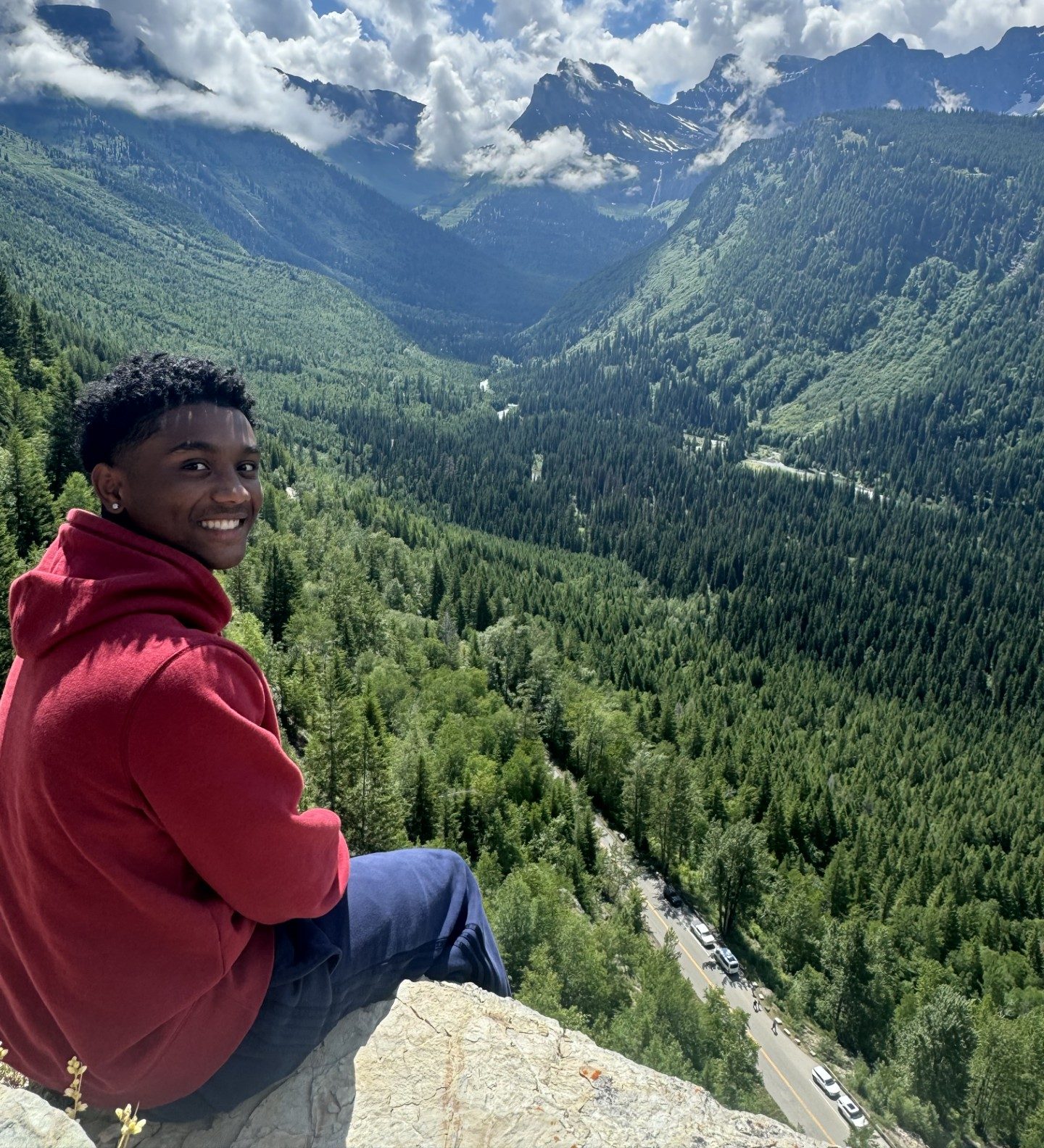 Scholar Hartman Warrick sits overlooking a valley full of trees.