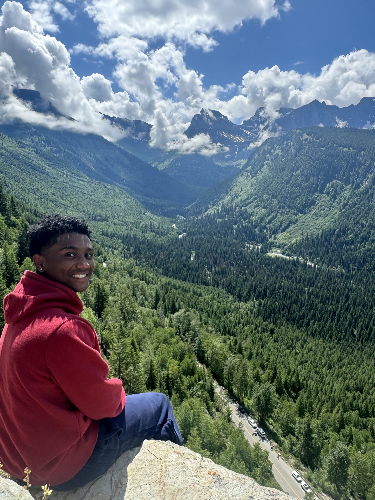 Scholar Hartman Warrick sits overlooking a valley full of trees.